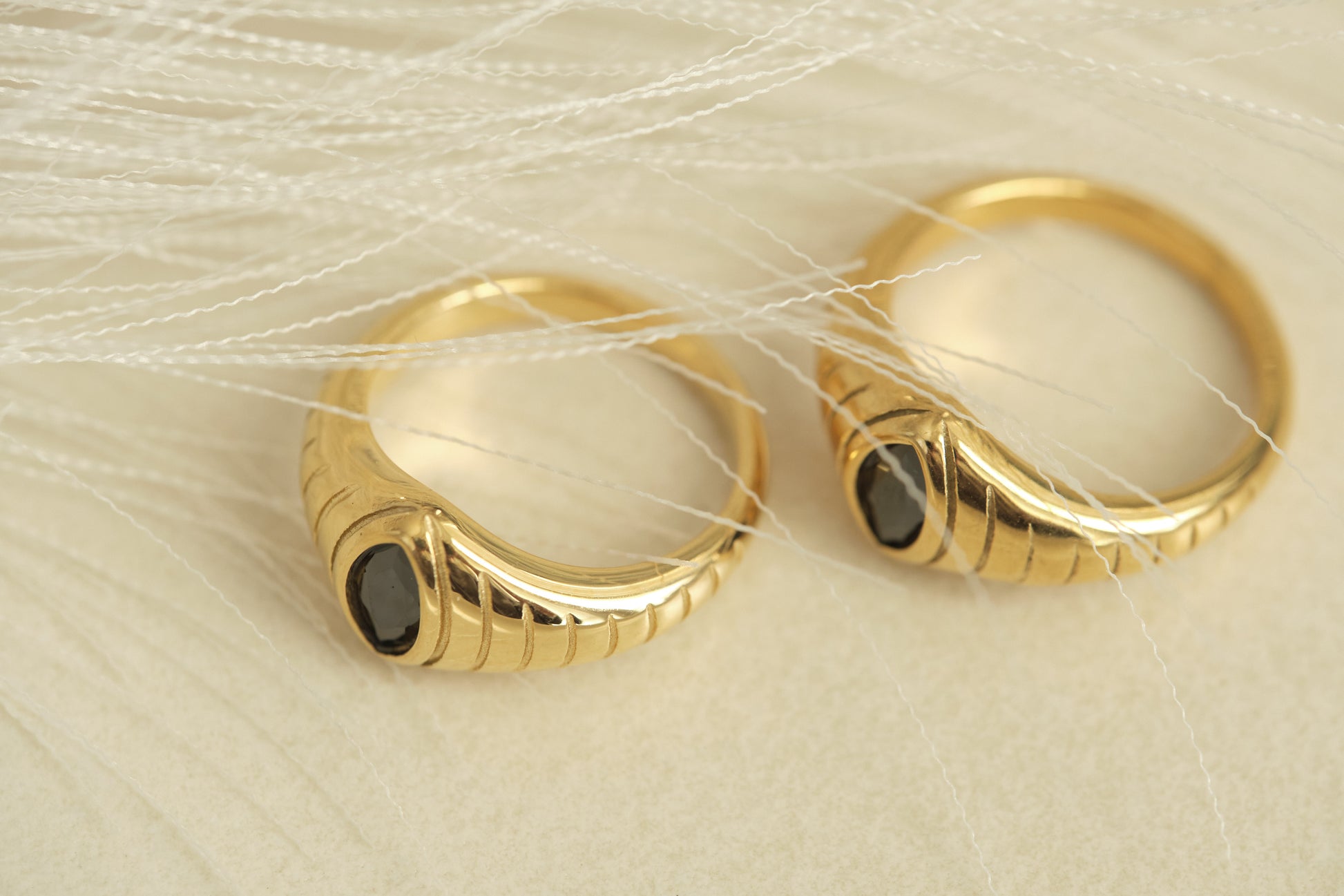 a pair of gold hoop earrings with black stones