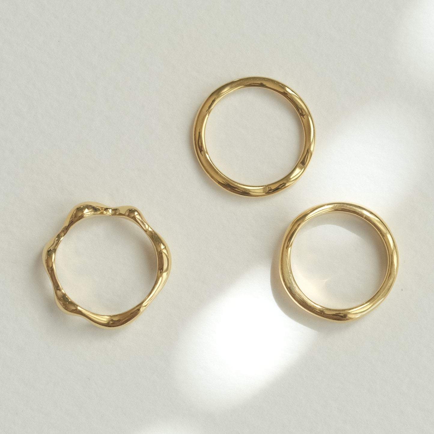 three gold rings on a white surface