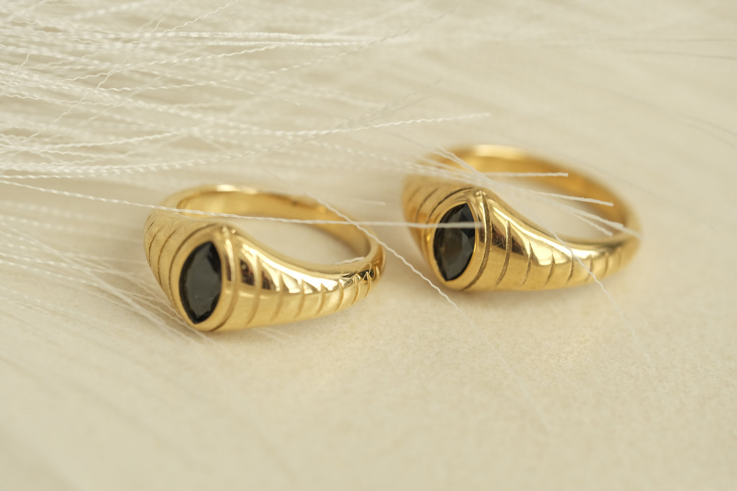 a pair of gold rings with a black stone