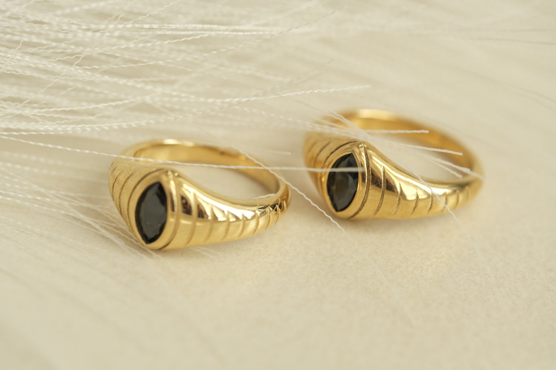 a pair of gold rings with a black stone